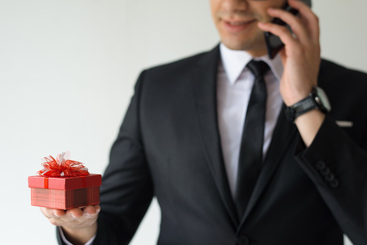 closeup business man holding gift box talking phone